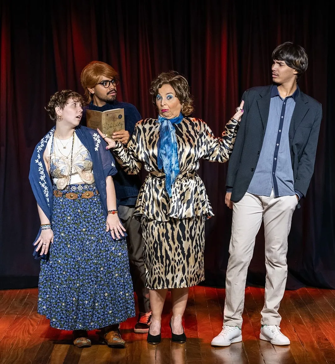 Quatro atores em cena diante de cortina vermelha, na comédia Novela Mexicana