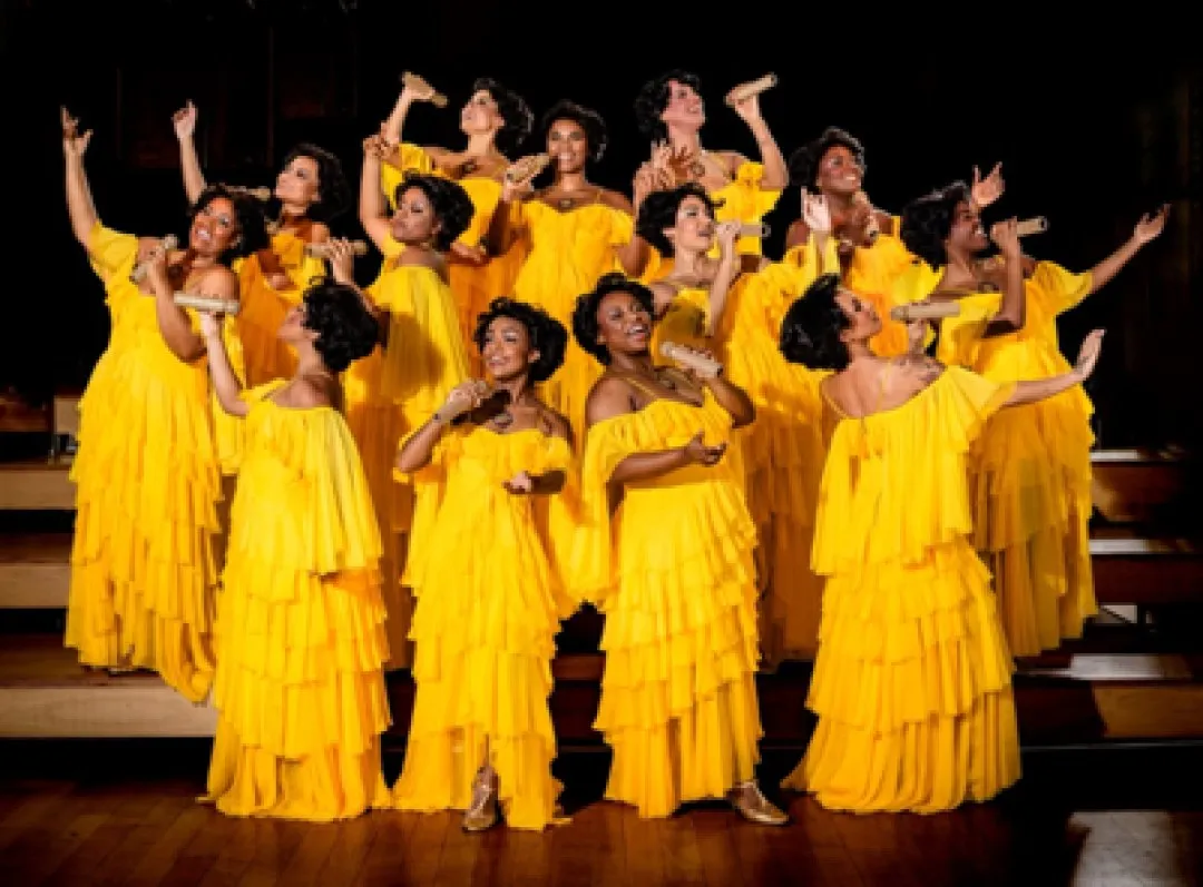 Elenco feminino de Marrom, o Musical, com vestidos amarelos de babados, em cena
